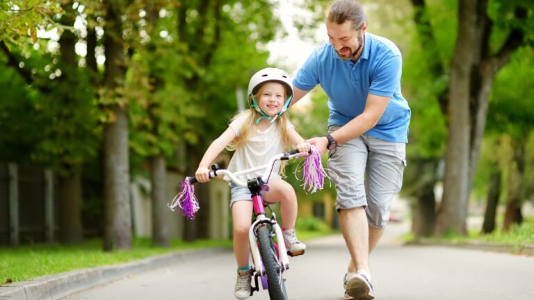 Pai ensinando filha a andar de bicicleta.