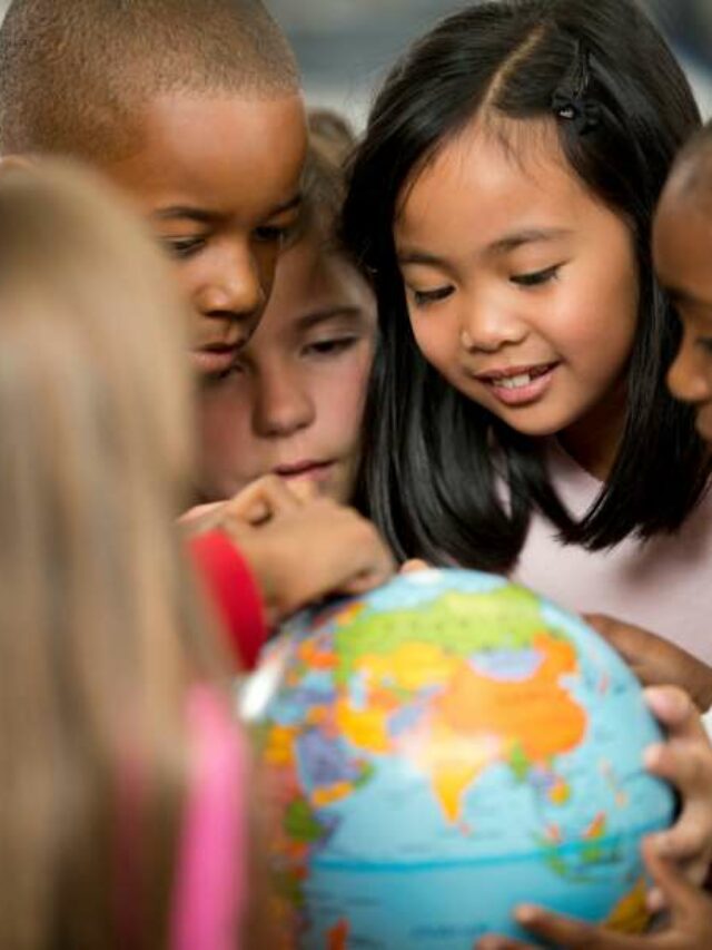 Alunos de escola bilíngue vendo globo mundial.