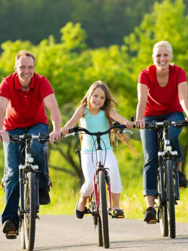 Família no parque fazendo passeio de bicicleta.